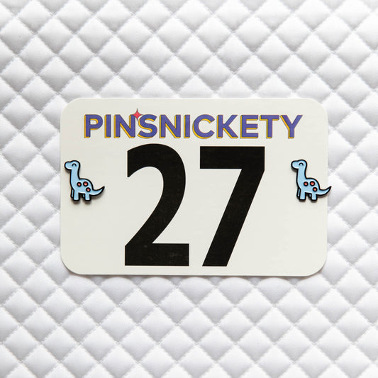 Pinsnickety Brontosaurus horse show number pins on a saddle pad.