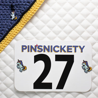 pinsnickety flying unicorn charm on a bonnet and horse show number pins on a saddle pad