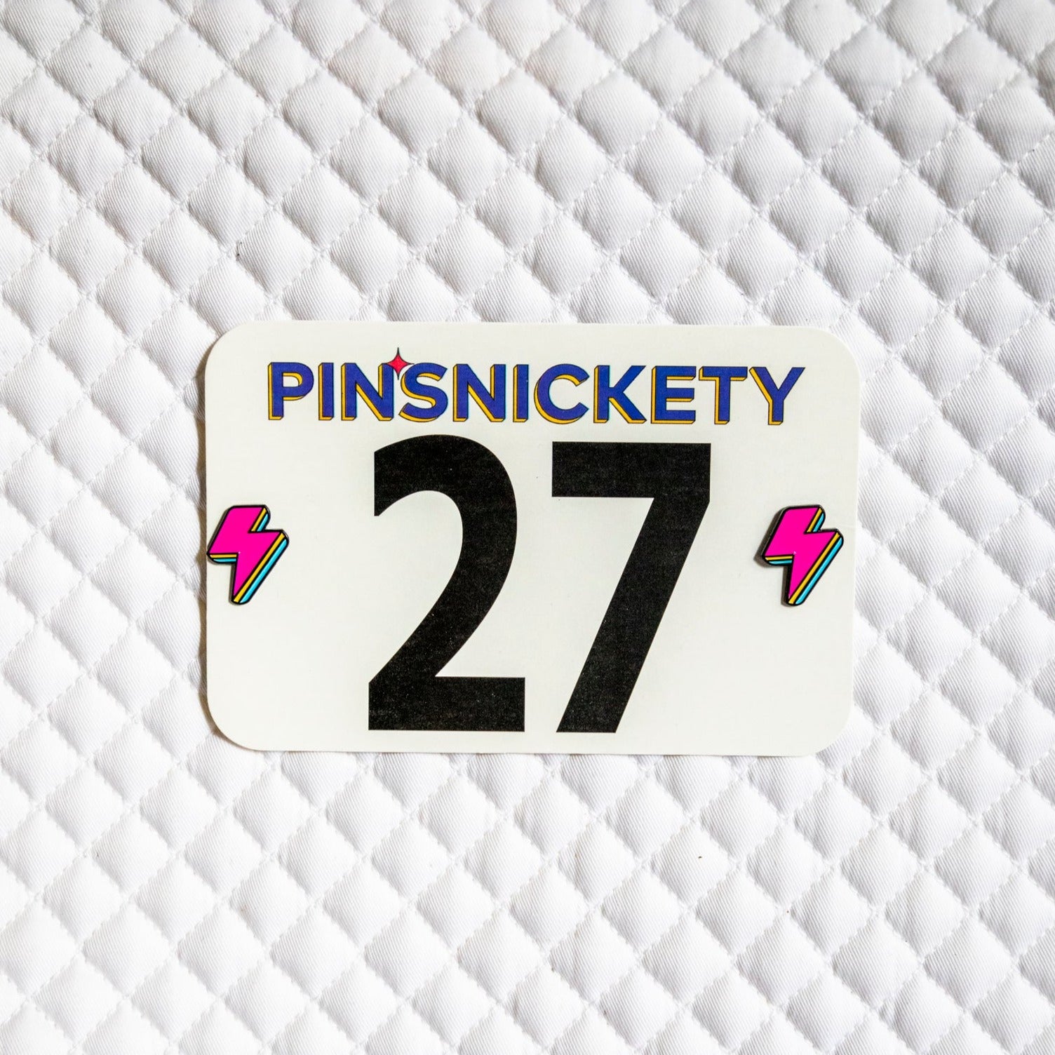 Pinsnickety Lightning Bolt horse show number pins on a saddle pad.