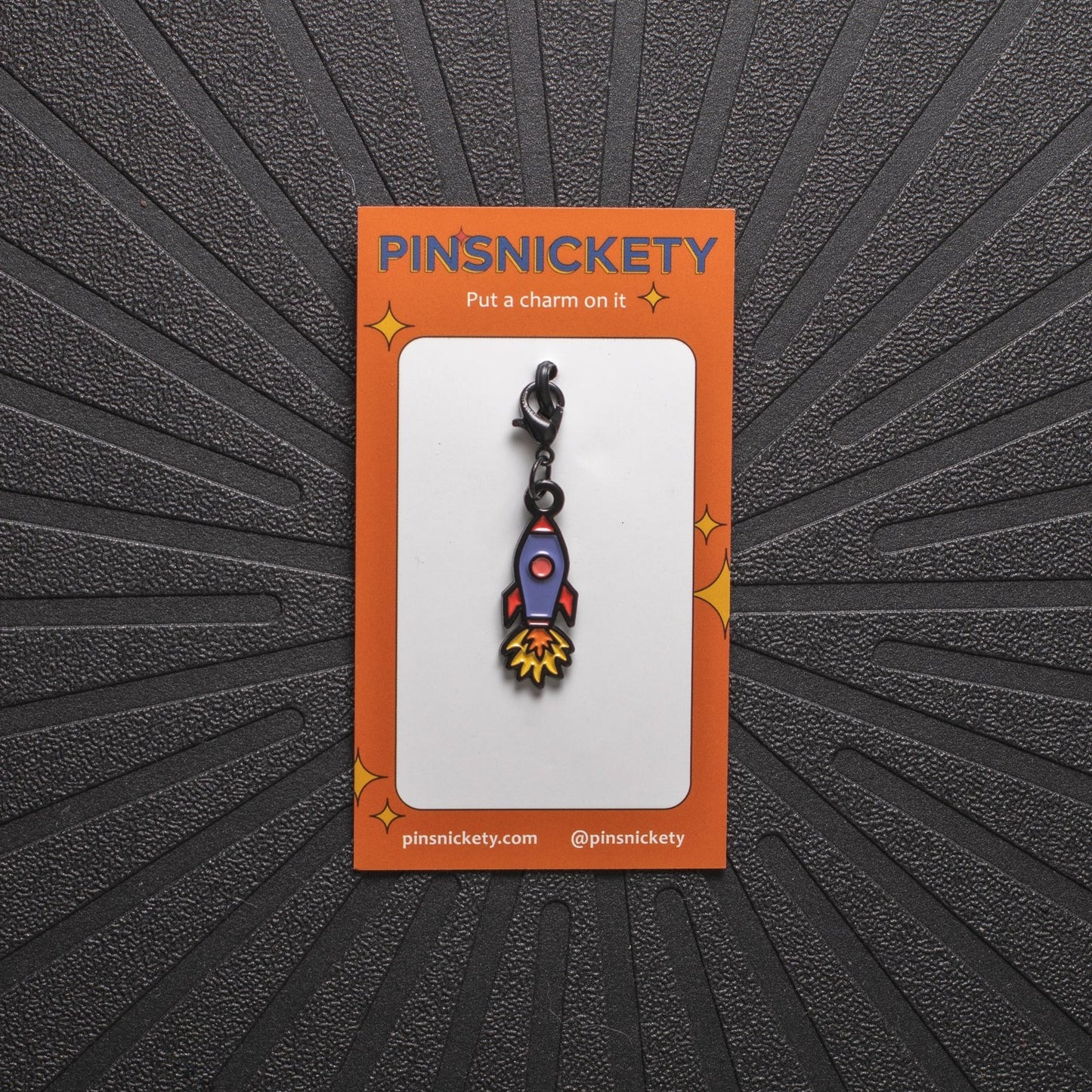 Pinsnickety rocket ship charm on its product packaging card