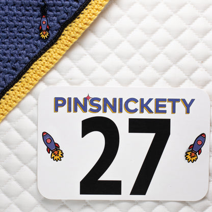 Pinsnickety Rocket Ship charm and horse show number pins on a bonnet and saddle pad