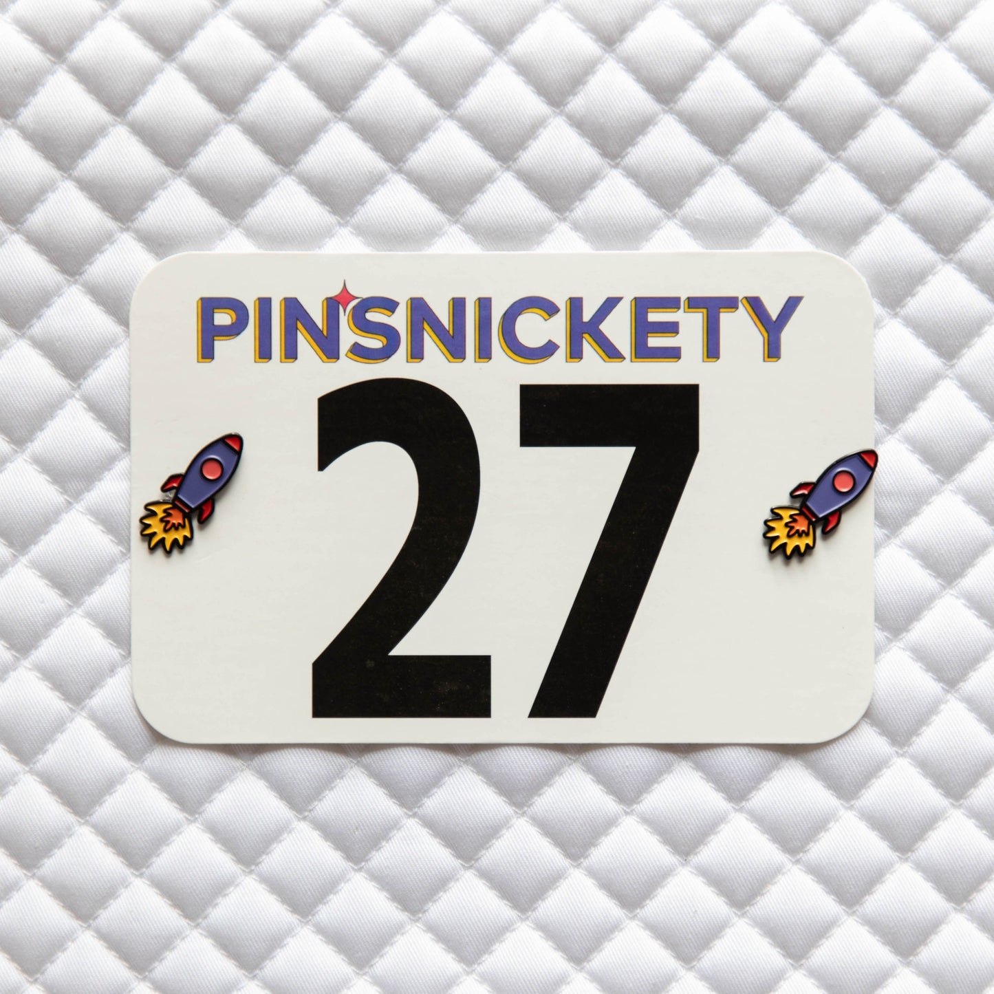 Pinsnickety Rocket Ship horse show number pins on a saddle pad
